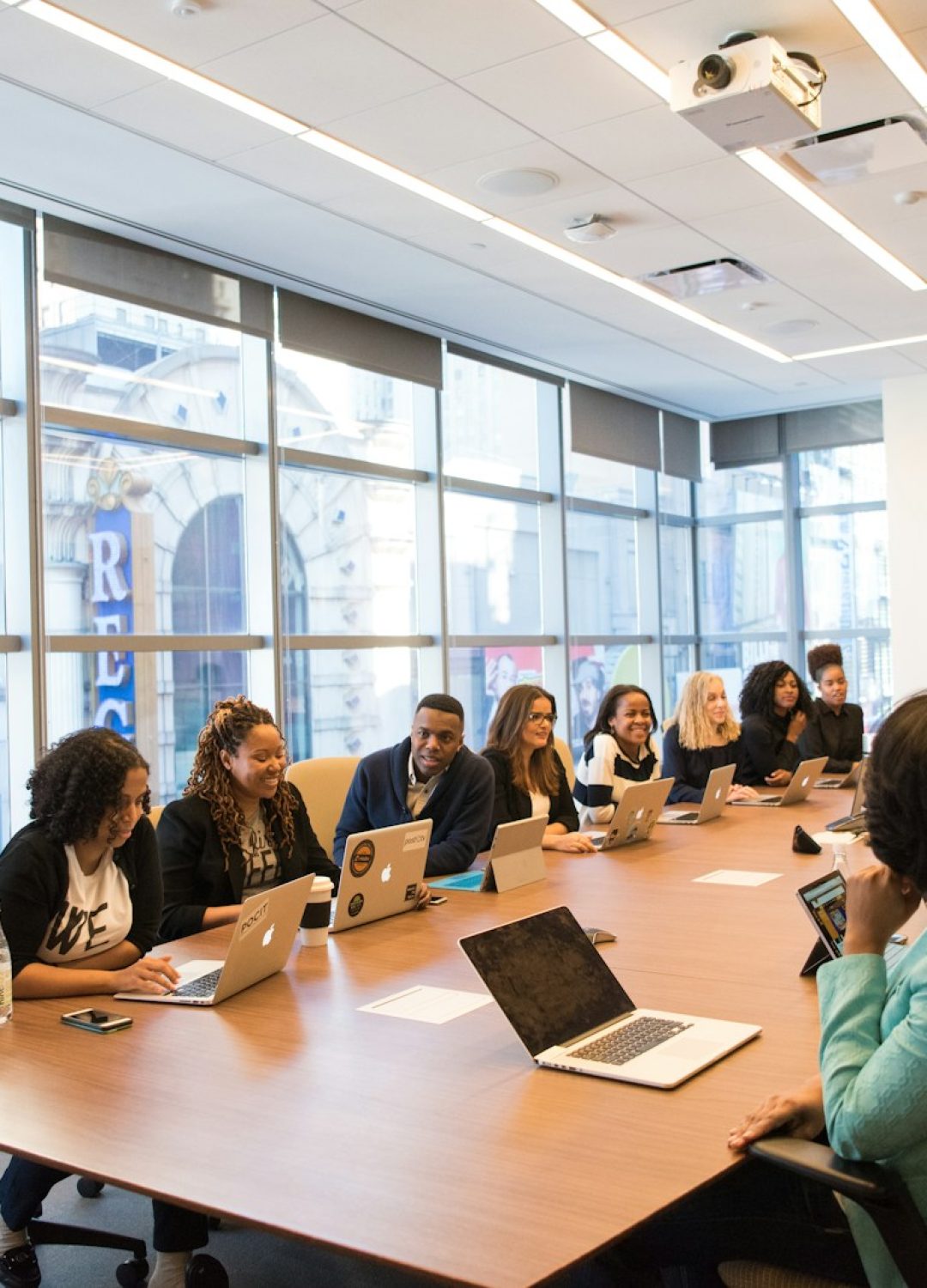 group of people sitting beside rectangular wooden table with laptops