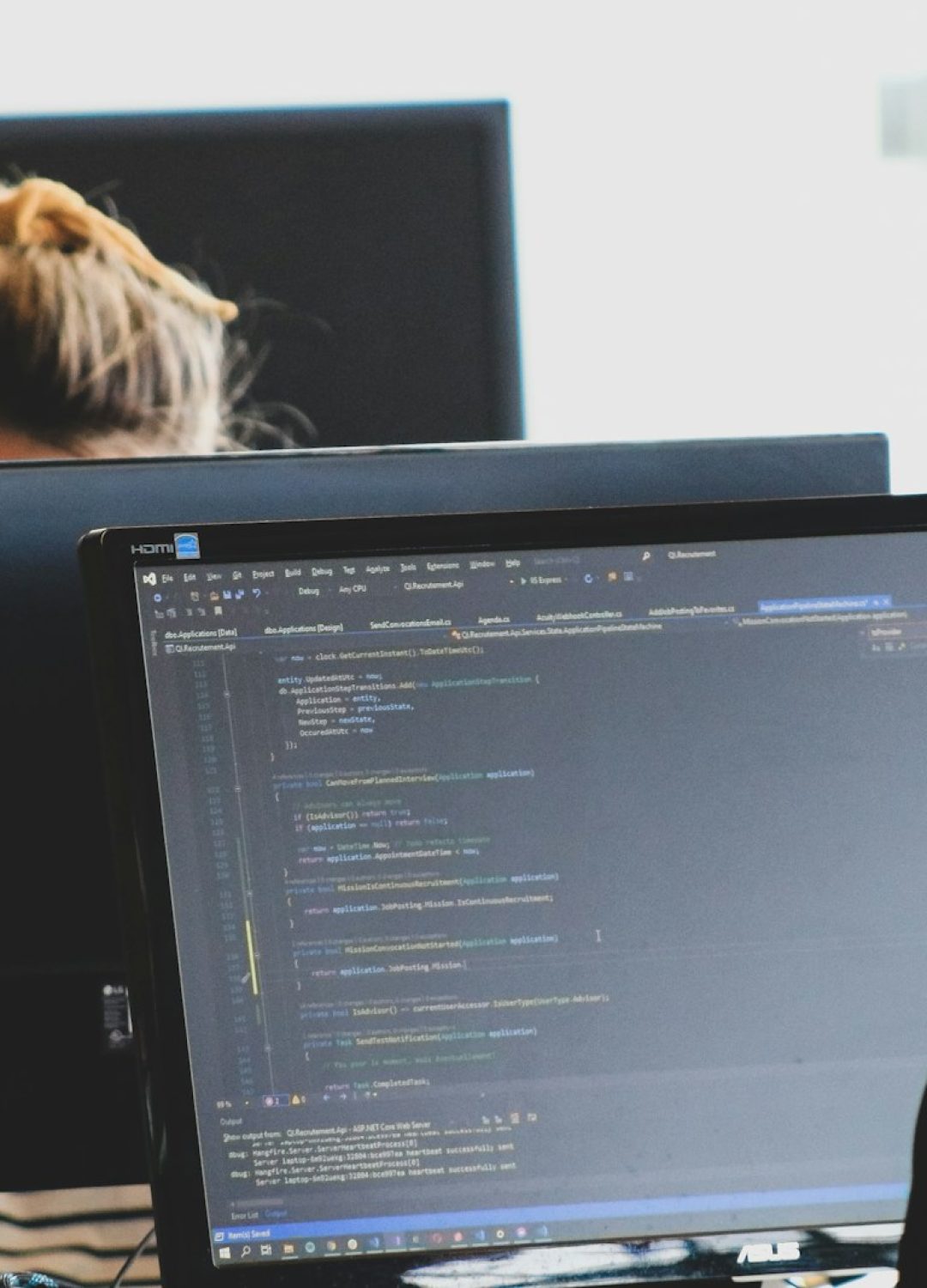 woman in black shirt sitting beside black flat screen computer monitor