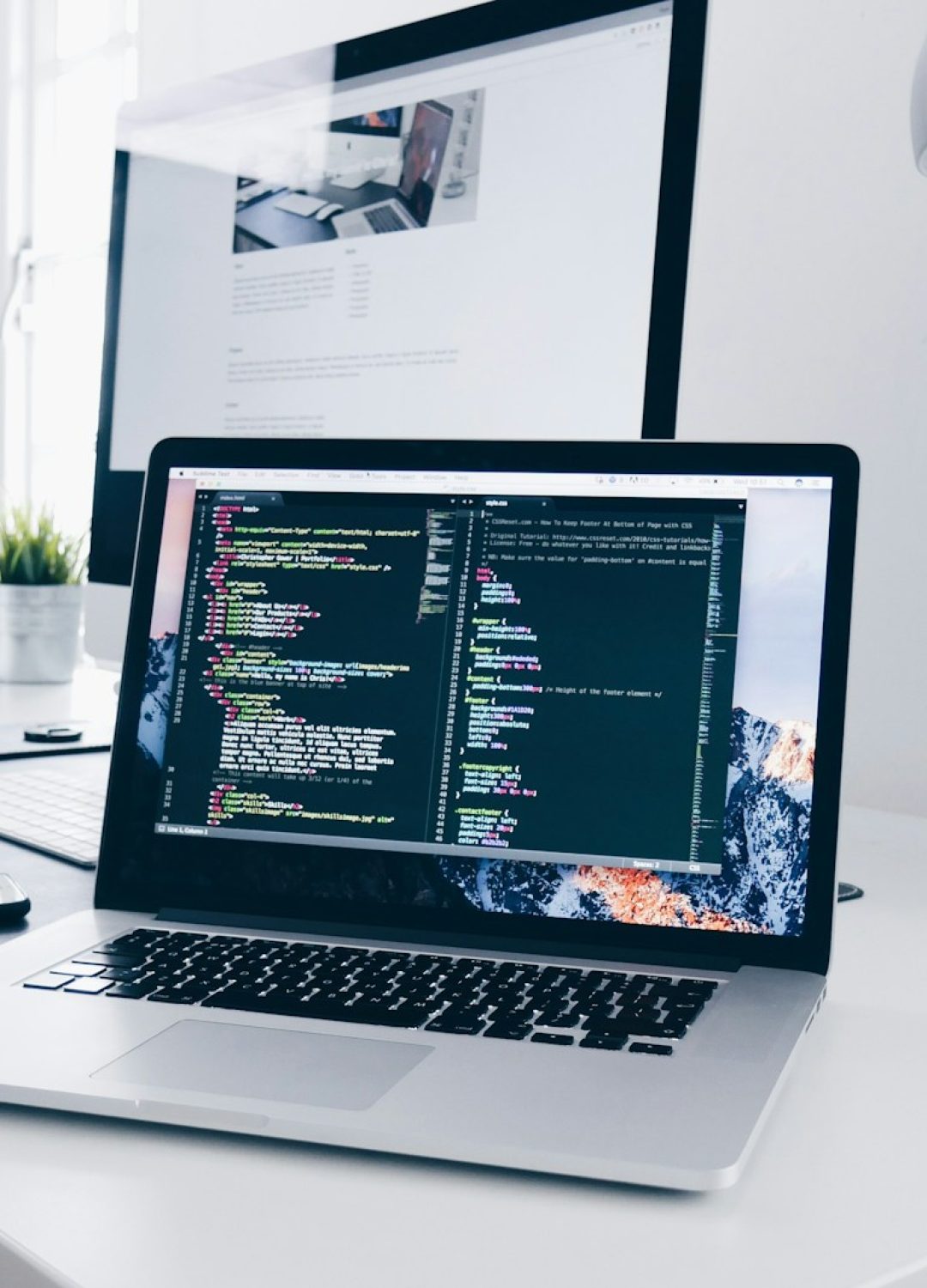A MacBook with lines of code on its screen on a busy desk