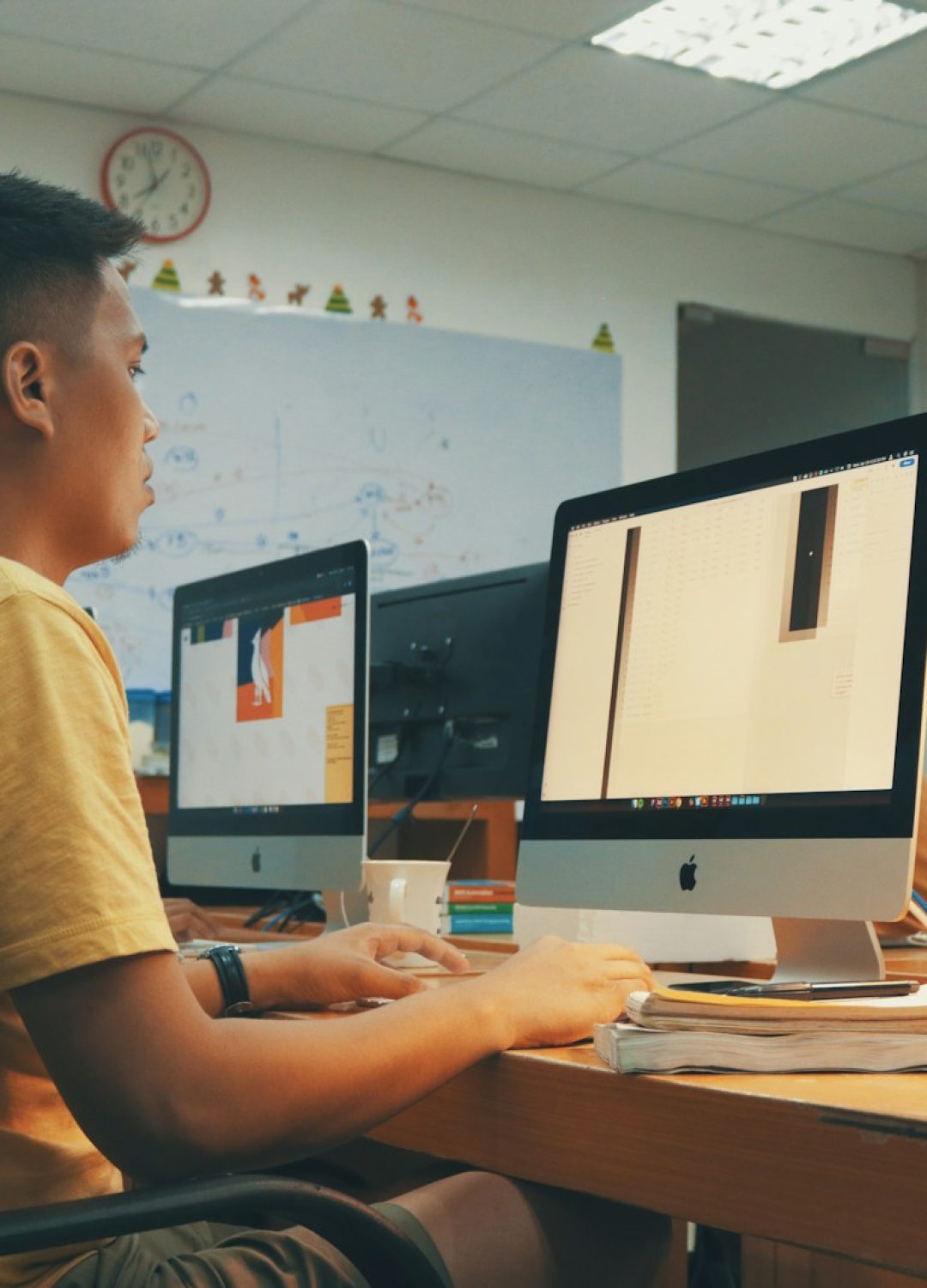 man using Apple desktop inside room beside man